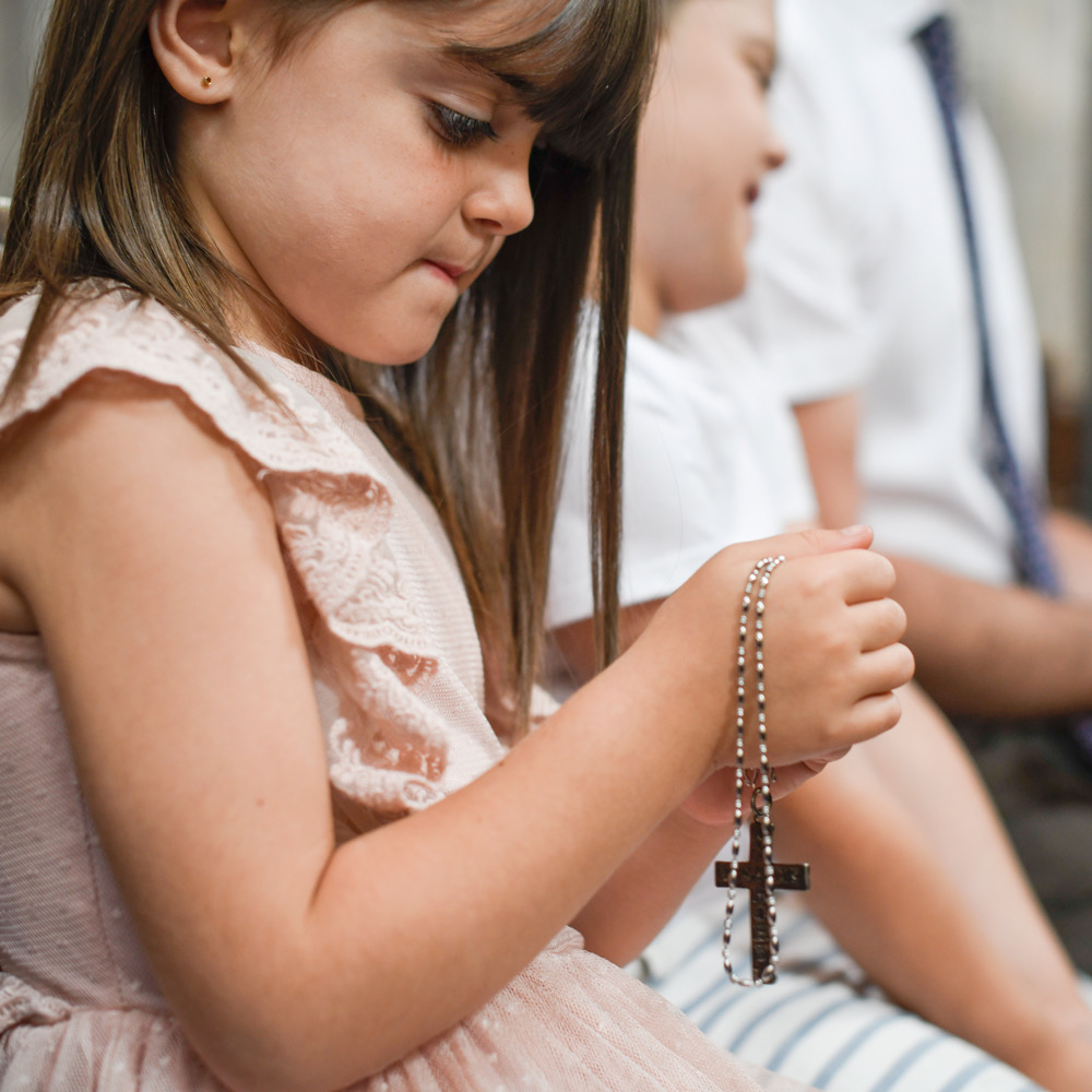 A child quietly praying with a rosary